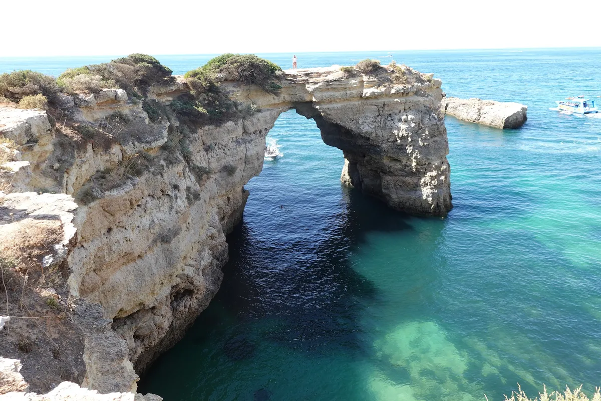 Arco de rocha sobre água turquesa na costa do Algarve